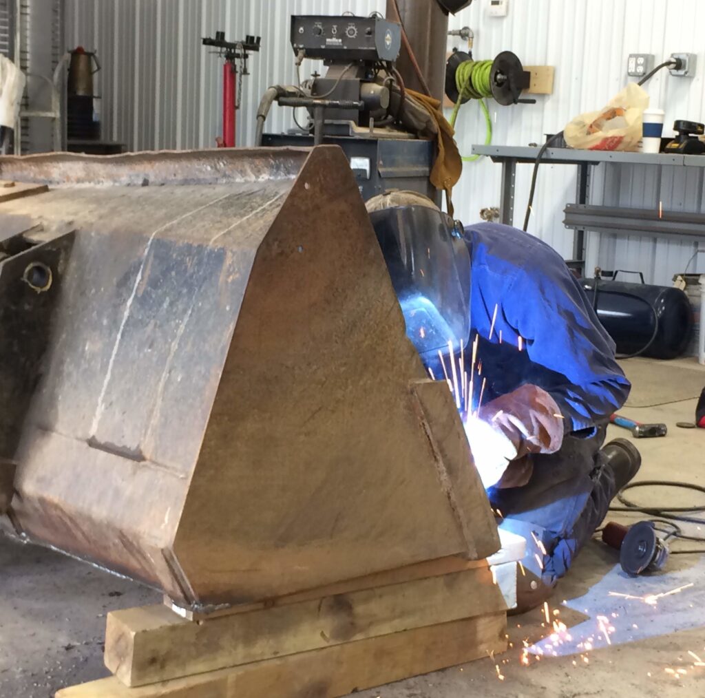man welding steel bucket