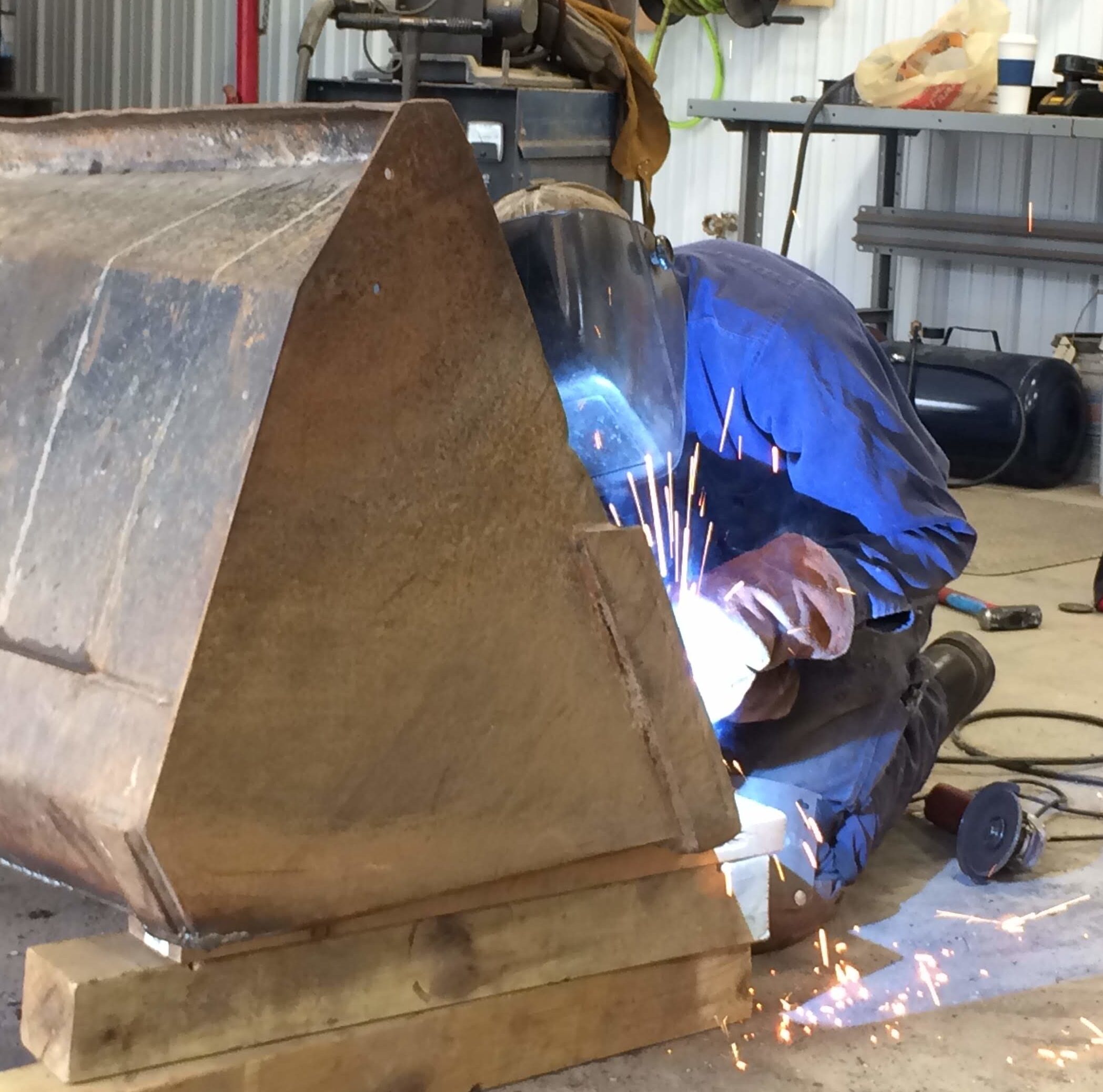 Man welding tractor bucket